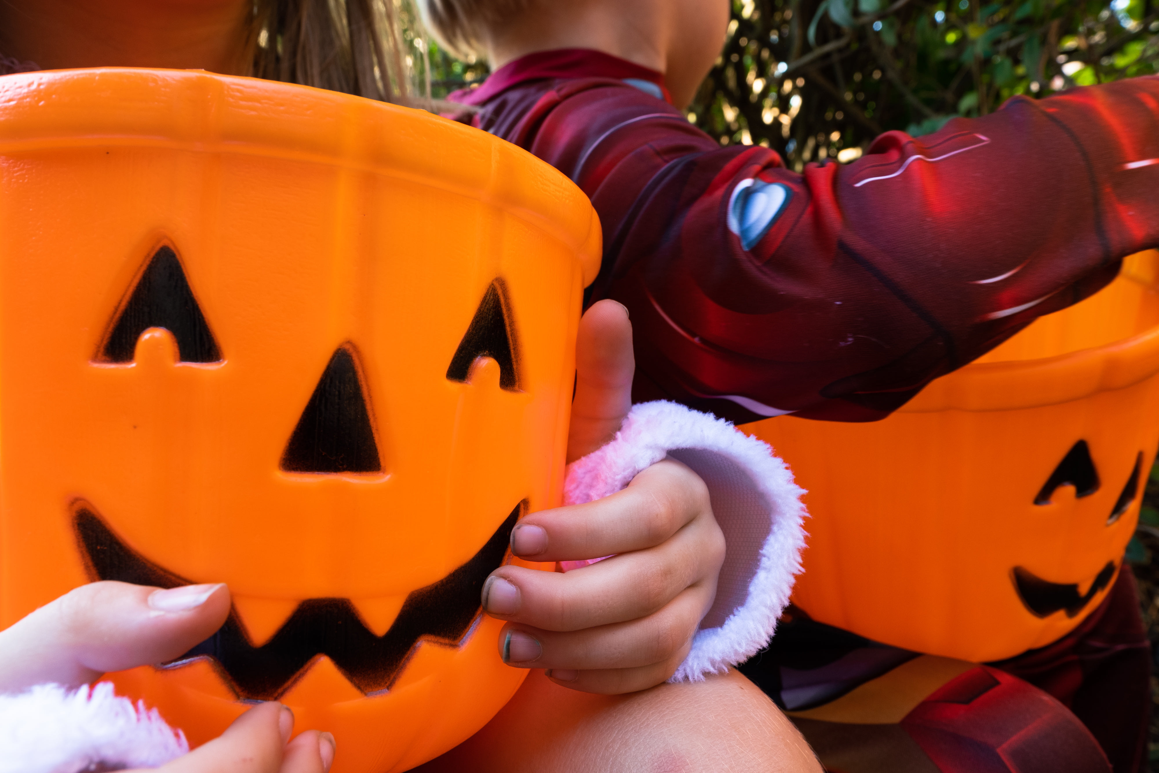 children holding plastic trick-or-treat buckets