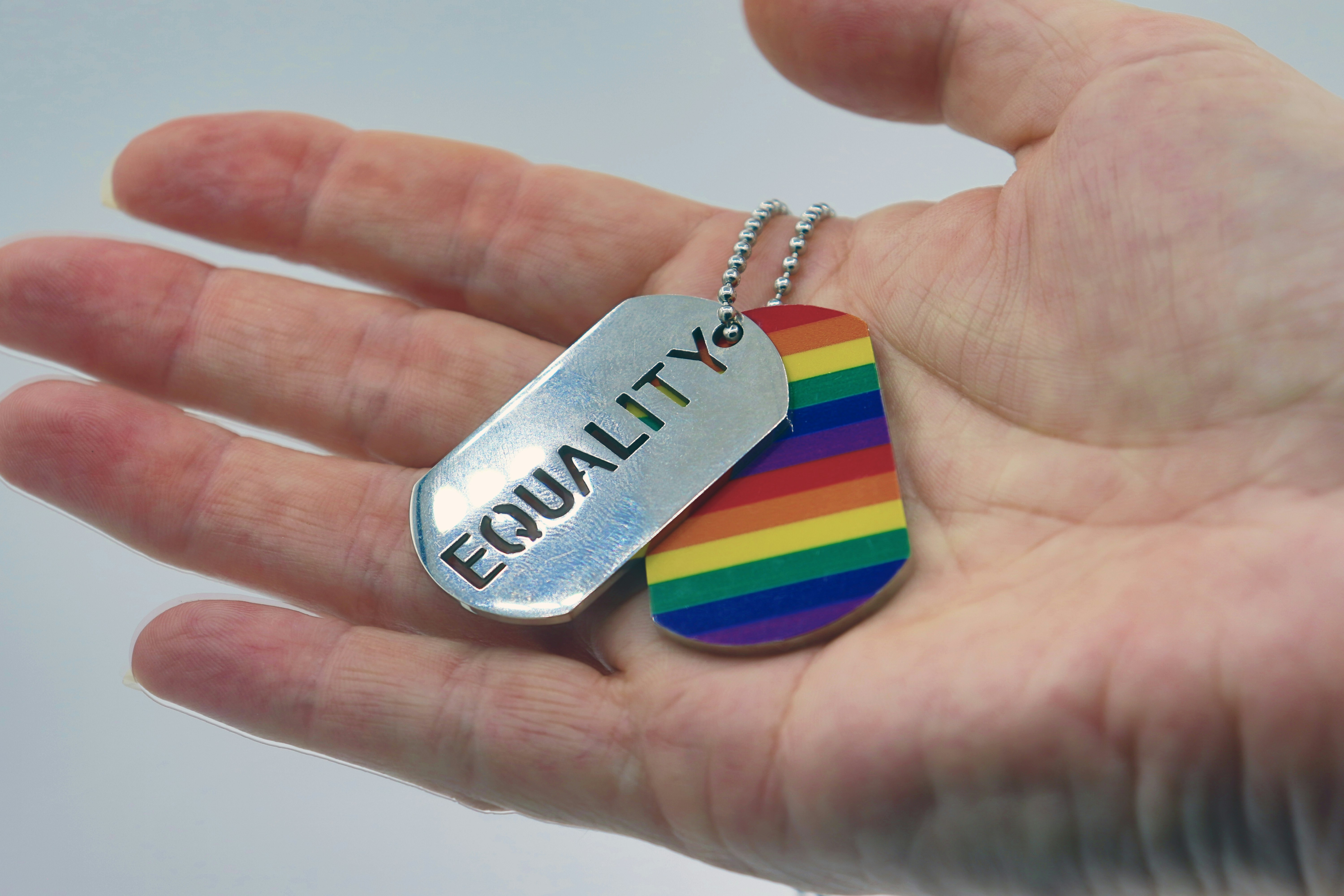A hand holding two keychains-- one rainbow, one stating \'equality\'.