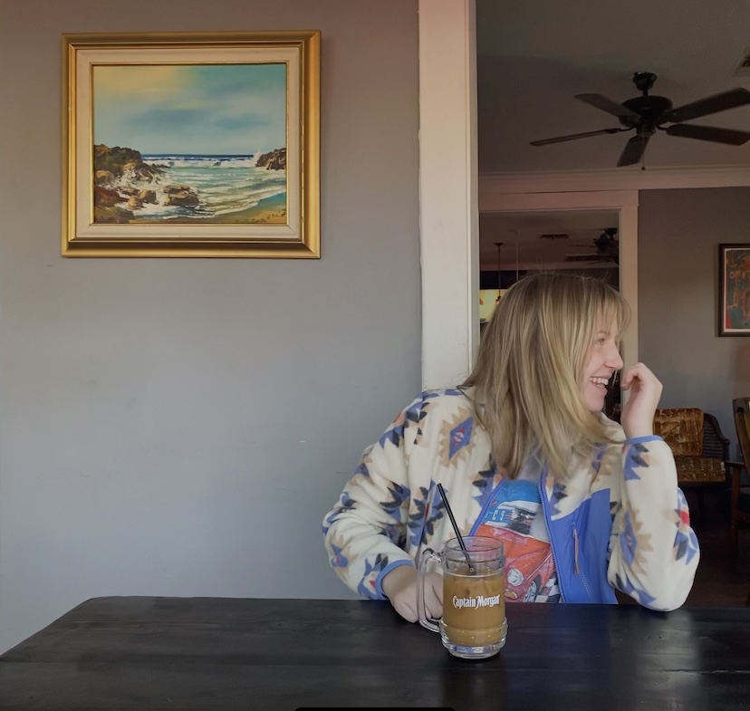 Chapter member sitting in a coffee shop, in front of an iced latte