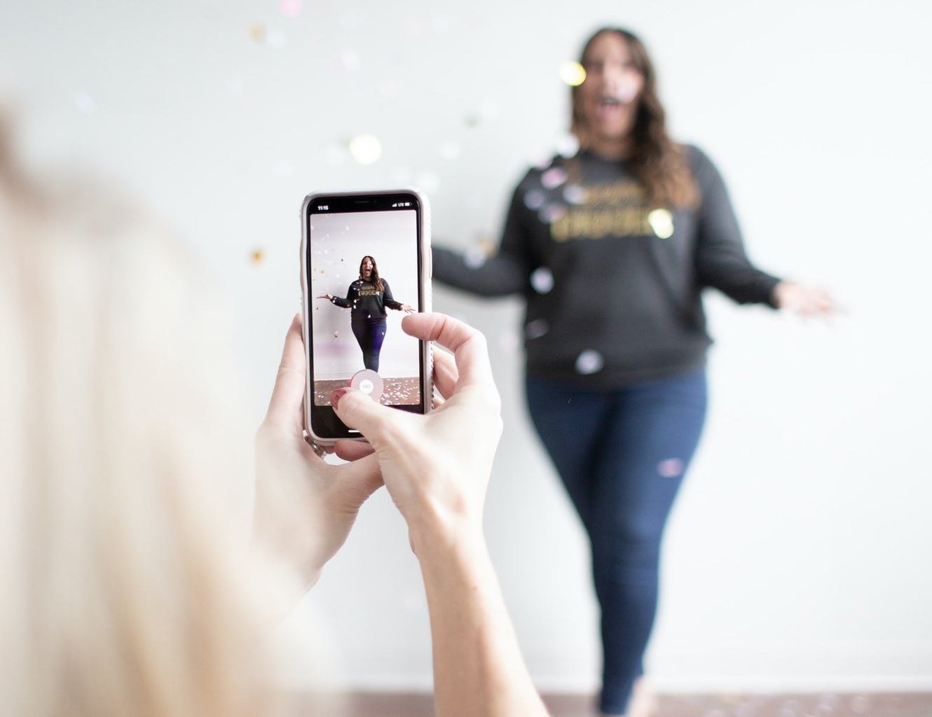 woman filming vertical video of woman throwing confetti