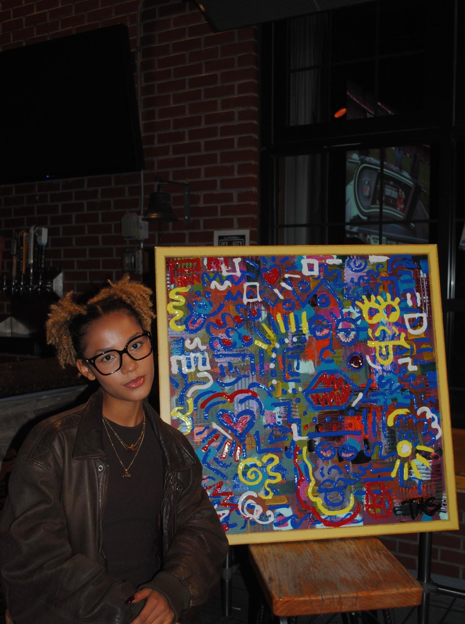 TATUM THE ARTIST posing in front of one of her works