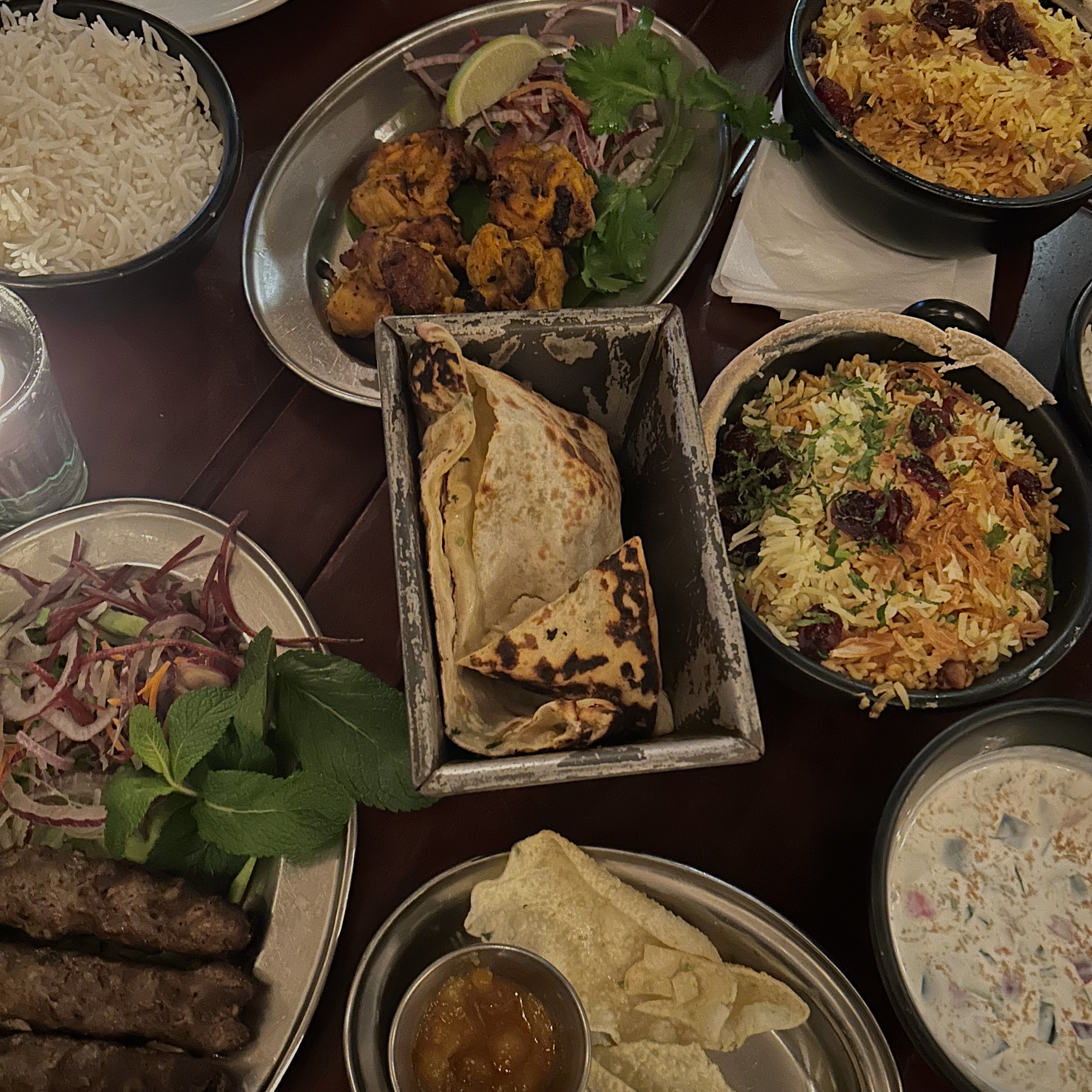 A table of food featuring plates of meat and rice dishes