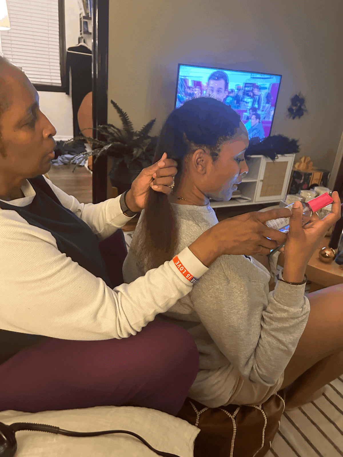 My mom using Luster’s Pink Glosser after blow drying my sister’s hair (Faith Harper/Her Campus Howard).