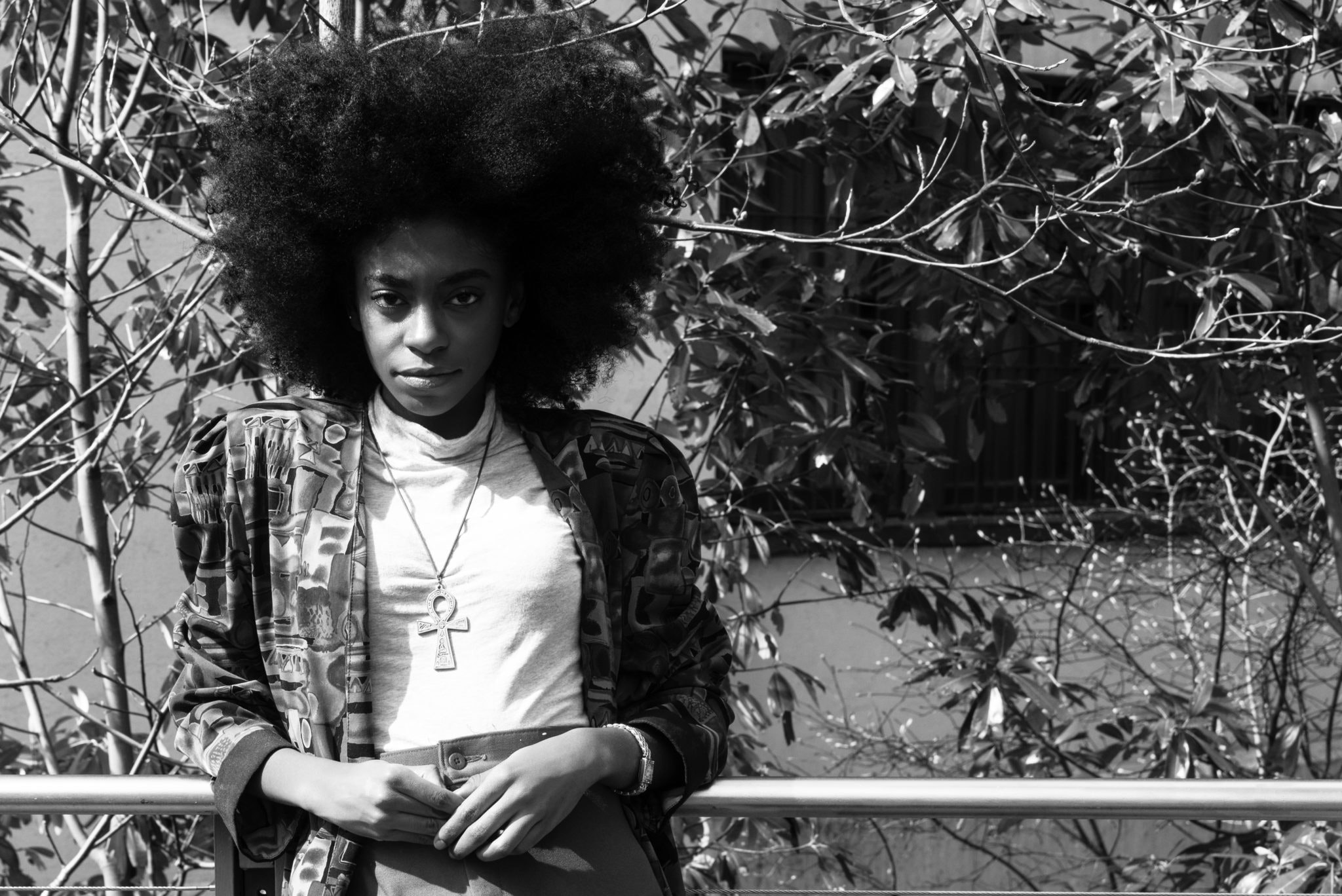 greyscale photo of a woman leaning on a fence