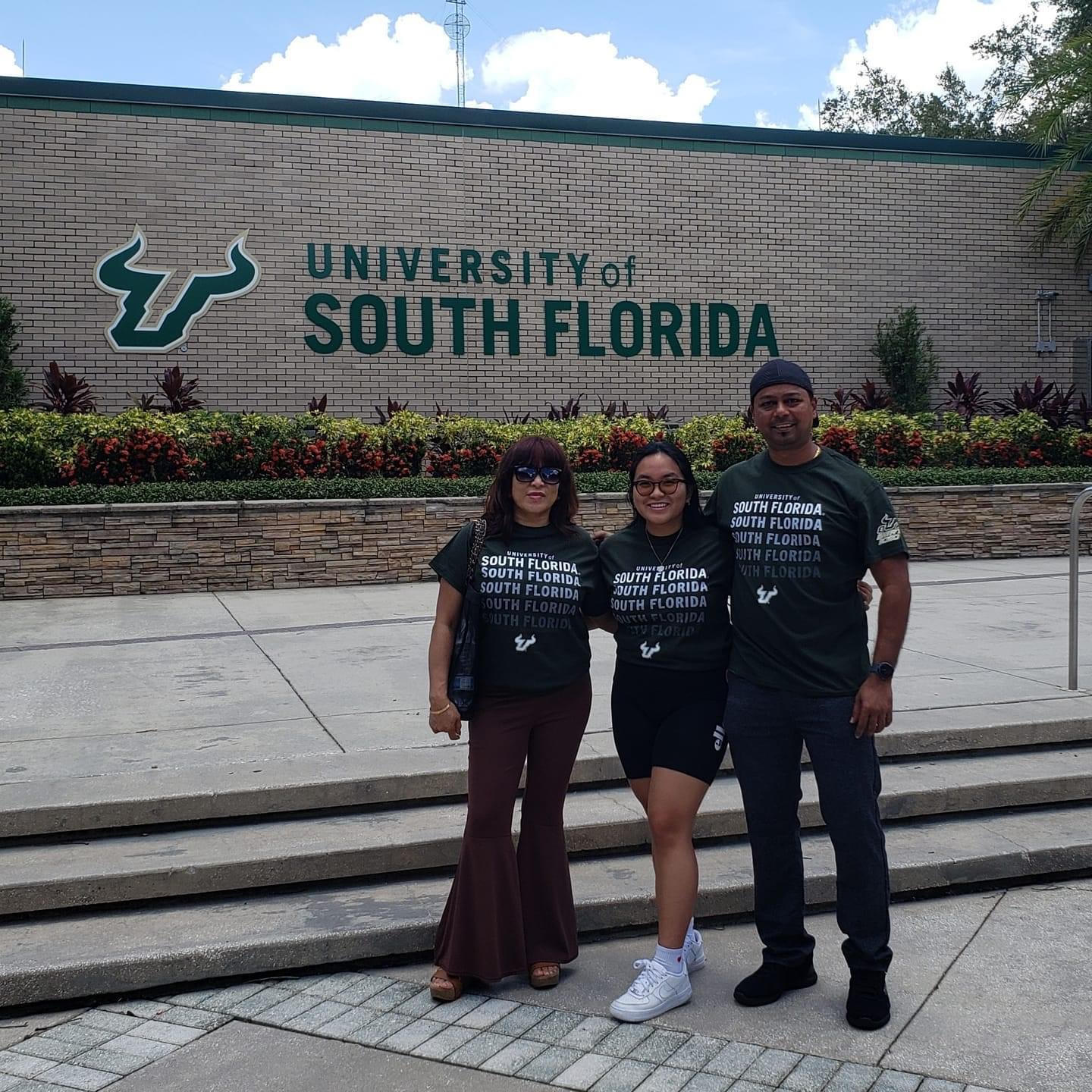 Parents and daughter in front of USF sign